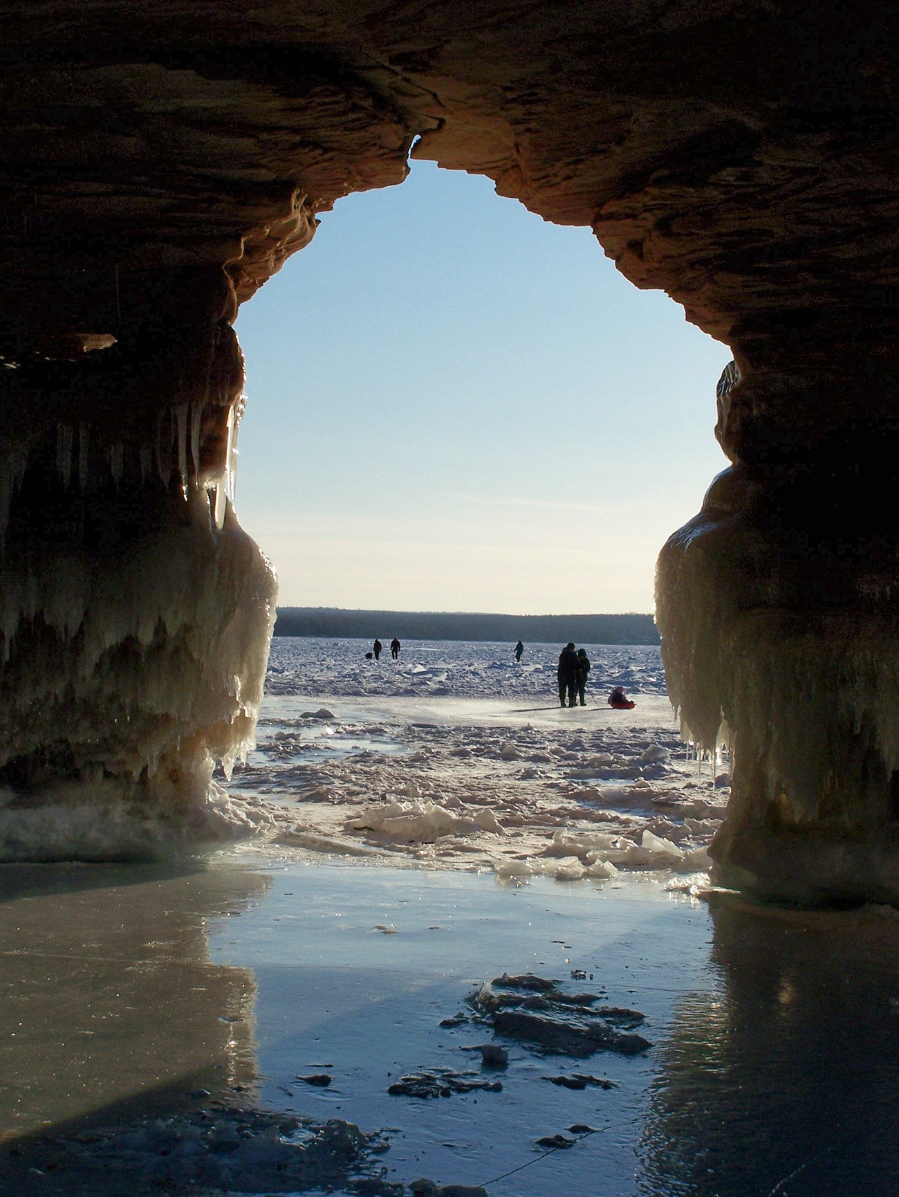 A cave entrance leads out to a frozen lake.