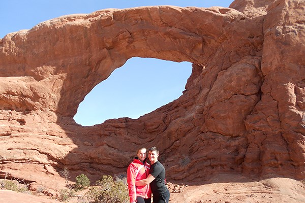 Man and woman pose in front of "The Windows" at Arches National Park in southeast Utah.