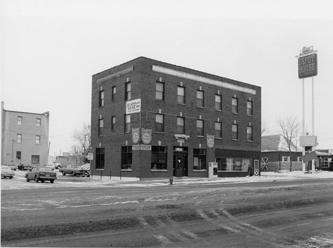 three story rectangular brick building with store front windows