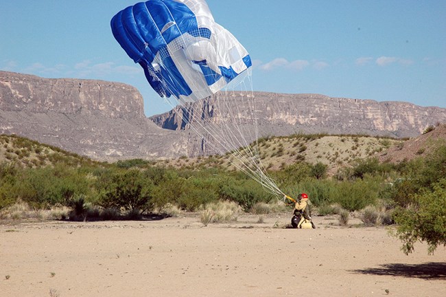 A smokejumper landing in a desert environment