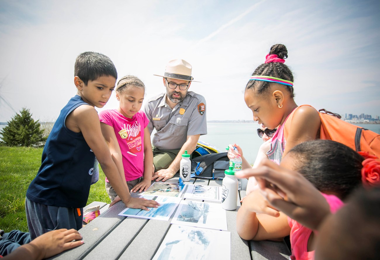 Kids sitting around table with park ranger.