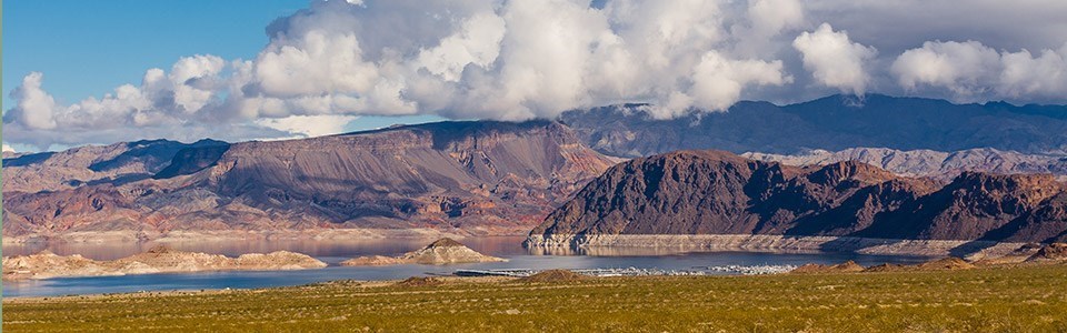 panoramic of mountains with lake in front and clouds above
