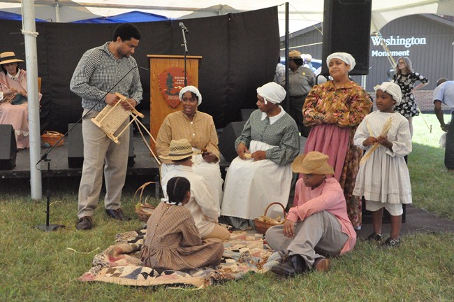 Juneteenth celebration at Booker T. Washington National Monument People in costumed interpretation rest by a podium.