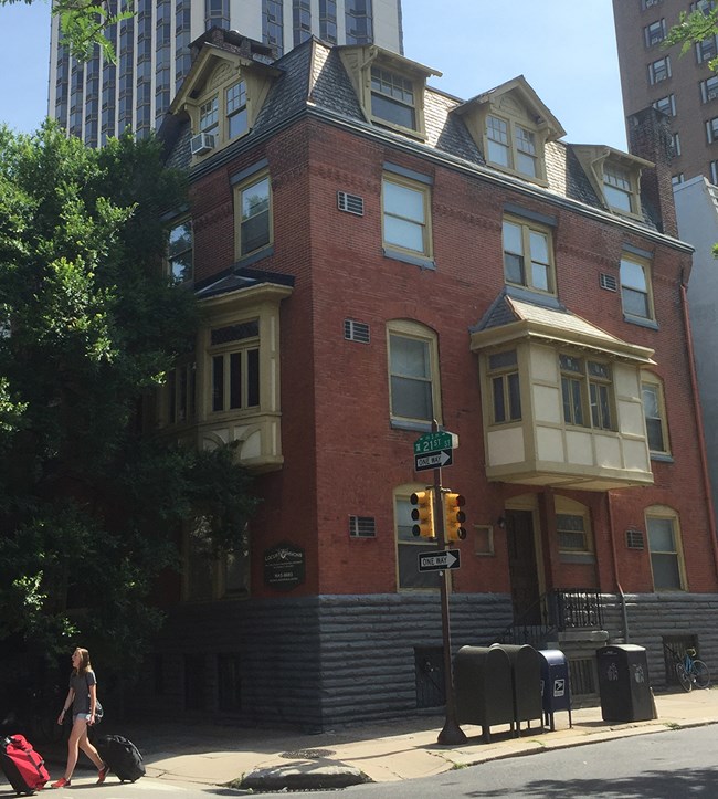 A multi-story brick home sits among the city buildings.