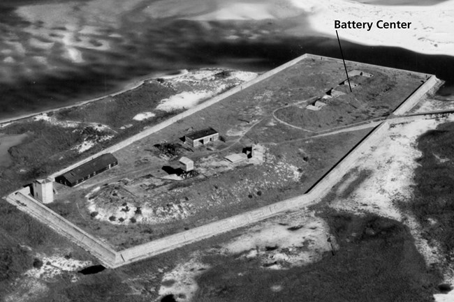 Black and white image of a barrier island with two low concrete structures surrounded by a seawall.