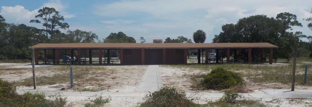 An open-air brick pavilion stands in the distance with showers in the foreground. An open-air brick pavilion stands in the distance with showers in the foreground.
