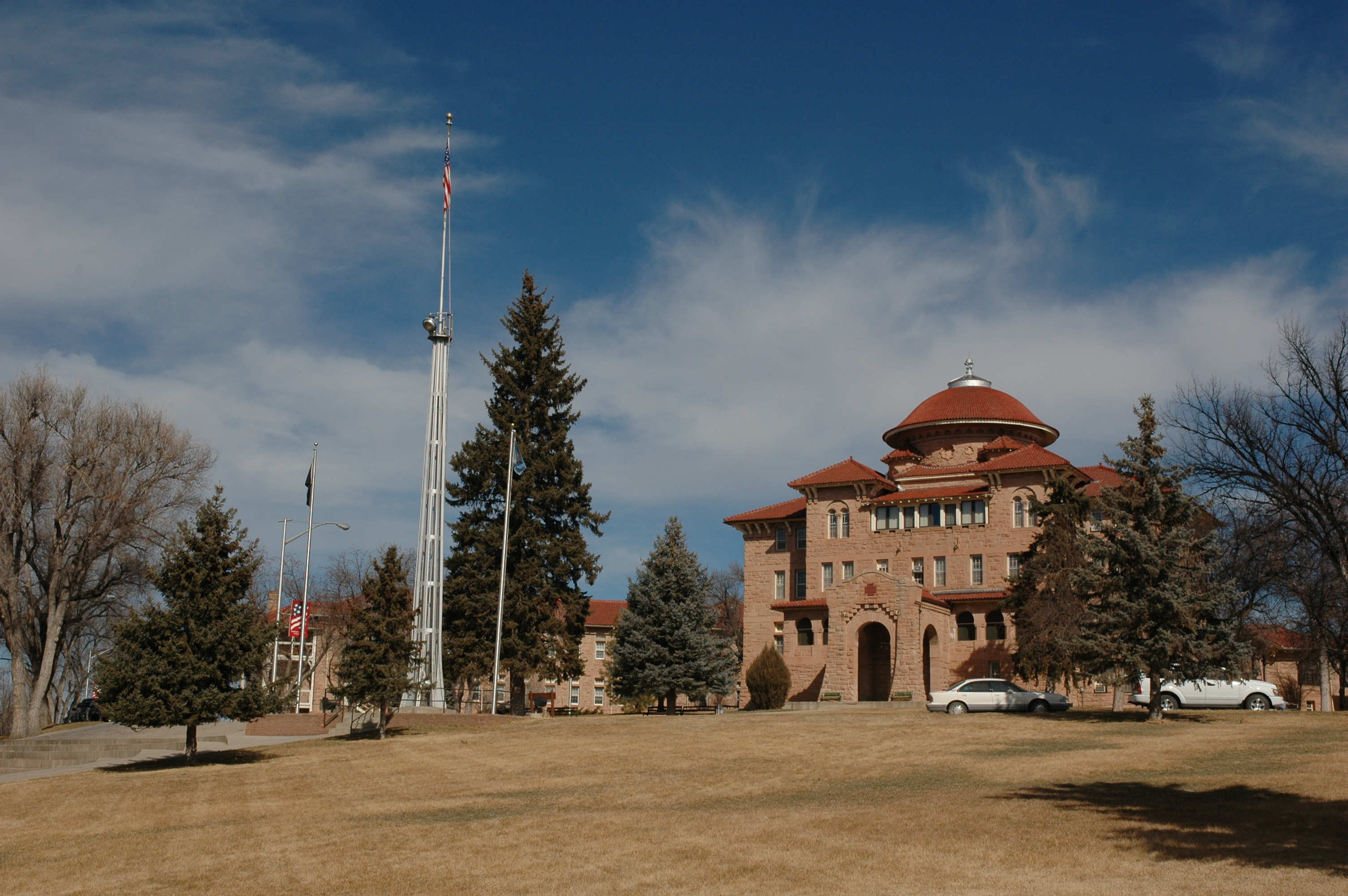 Tall brown building with a dome and red roof.