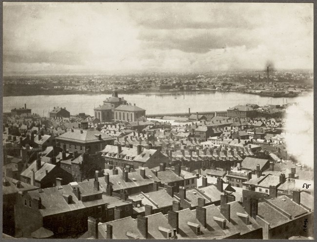 A view from above Beacon Hill looking towards the Charles Street Jail with only a view of the roofs of houses.