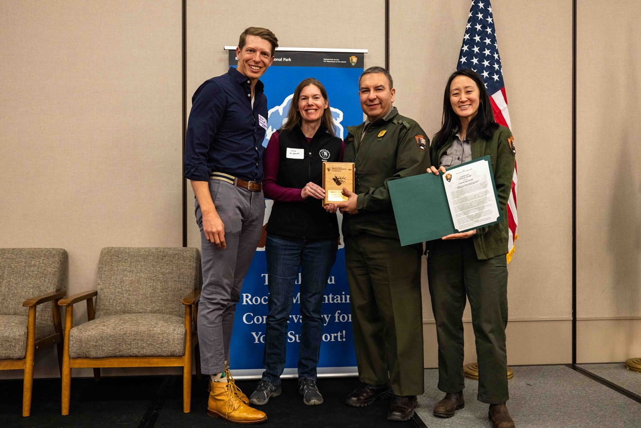 Two park staff present an award to two recipients