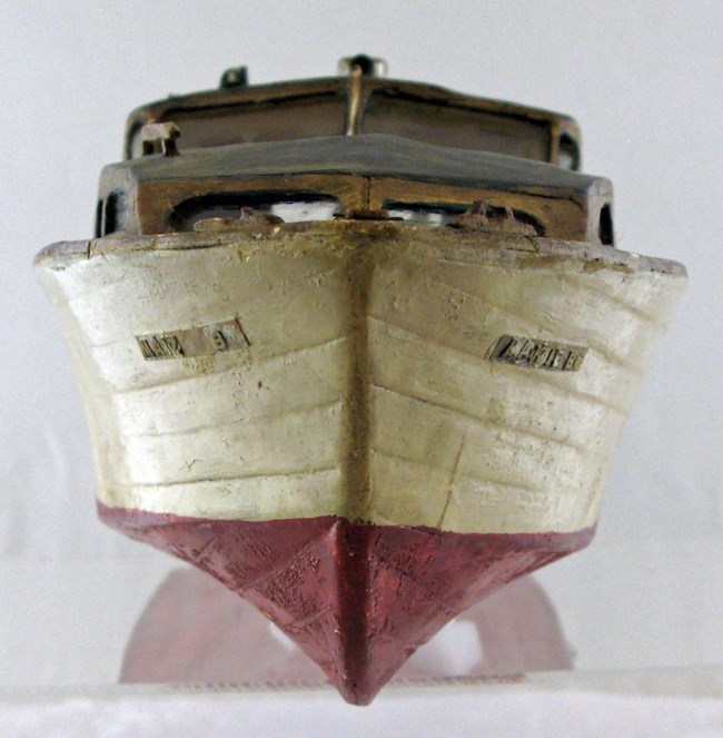 Image of wooden model boat painted white and red.