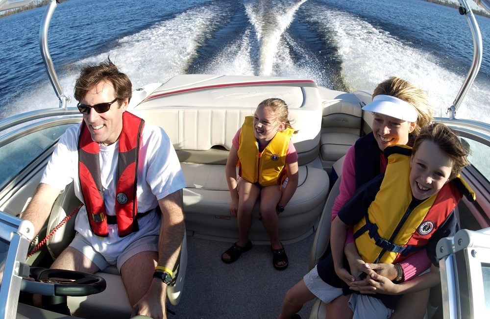 Family of four, all wearing life jackets and sitting in motor boat