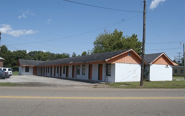 road side motel building with low roof line and a gravel parking lot