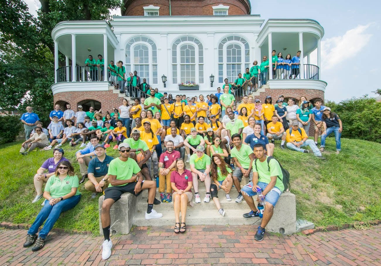 A large group of youth pose in front of historic home.