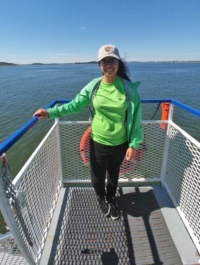 A young woman poses while standing on a boat.