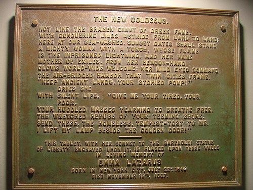 A bronze plaque with the words of the poem The New Colossus raised on it.