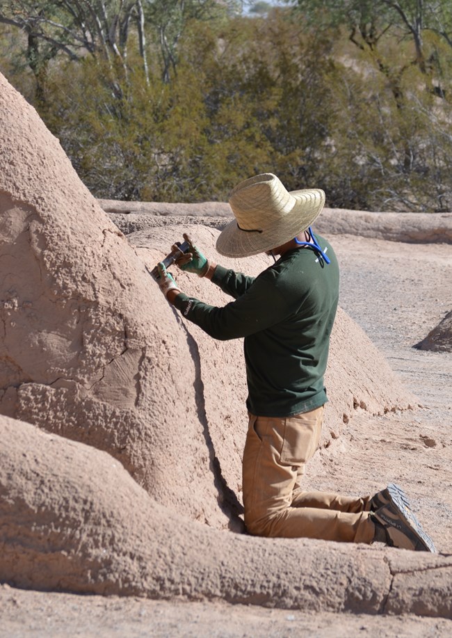 Employee doing preservation work on an abode wall