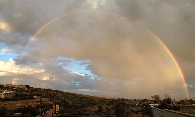 A full rainbow in a cloudy sky