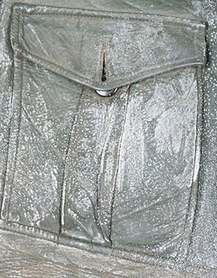 White fatty acid spew on the pocket of a green leather jacket.