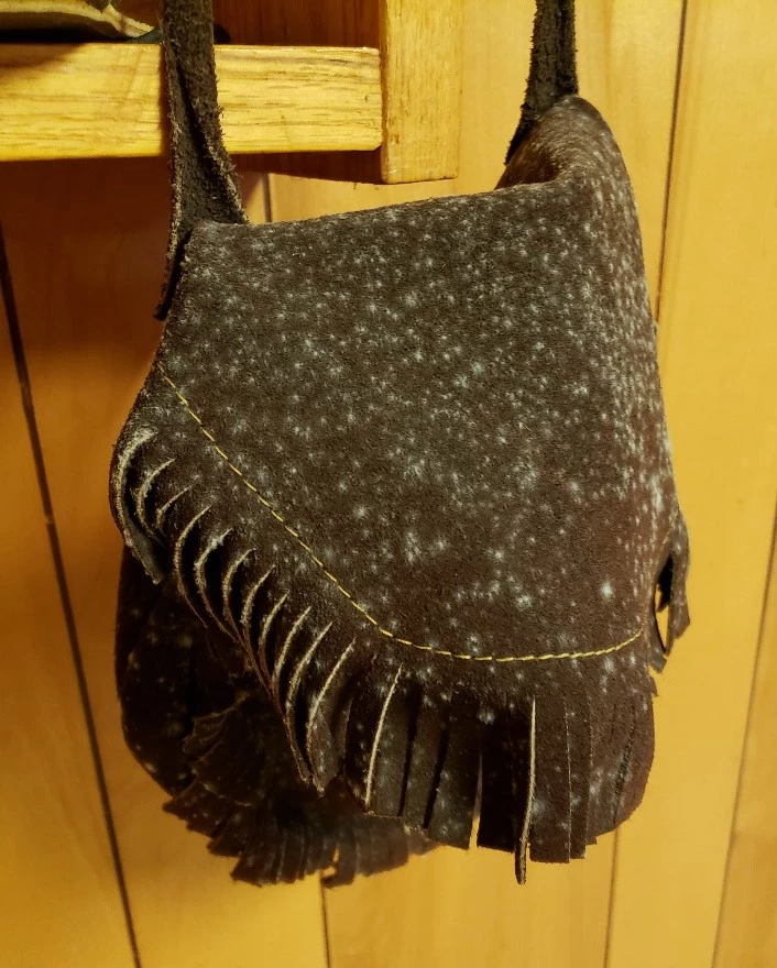 A brown leather ammunition bag with white mold growth throughout the surface. Note the mold has a dense center with extending growth.
