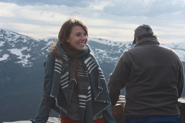 two people stand near an overlook of a mountain vista