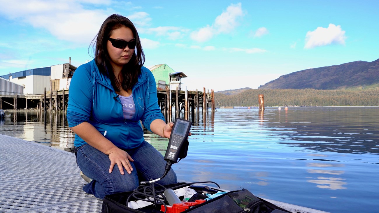 A person holds an electronic water testing device on a dock