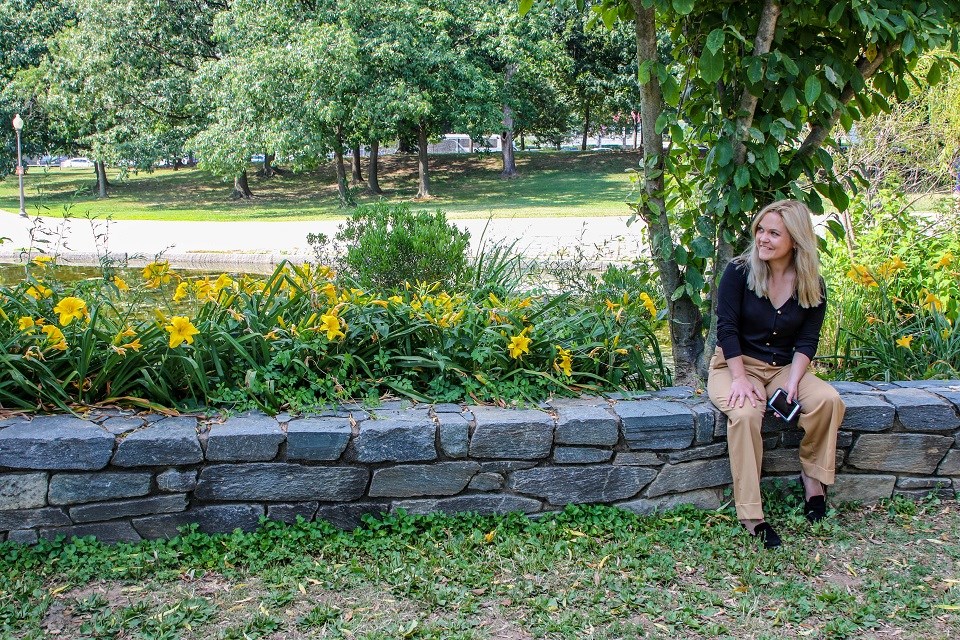 Visitor sitting on a stone wall lined with yellow flowers
