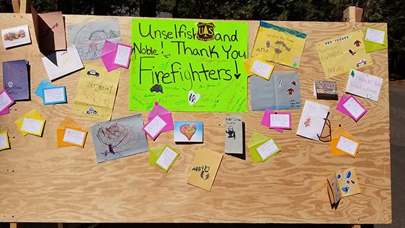 Camp Board Donnell Fire A fire camp board with bright colored thank you's and drawings for the firefighters is displayed.