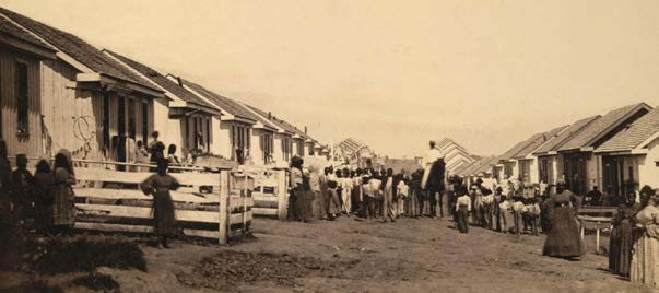 African American refugees standing outside refugee cottages at Camp Nelson