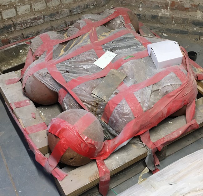 Cannonballs on a pallet covered in tape and plastic.