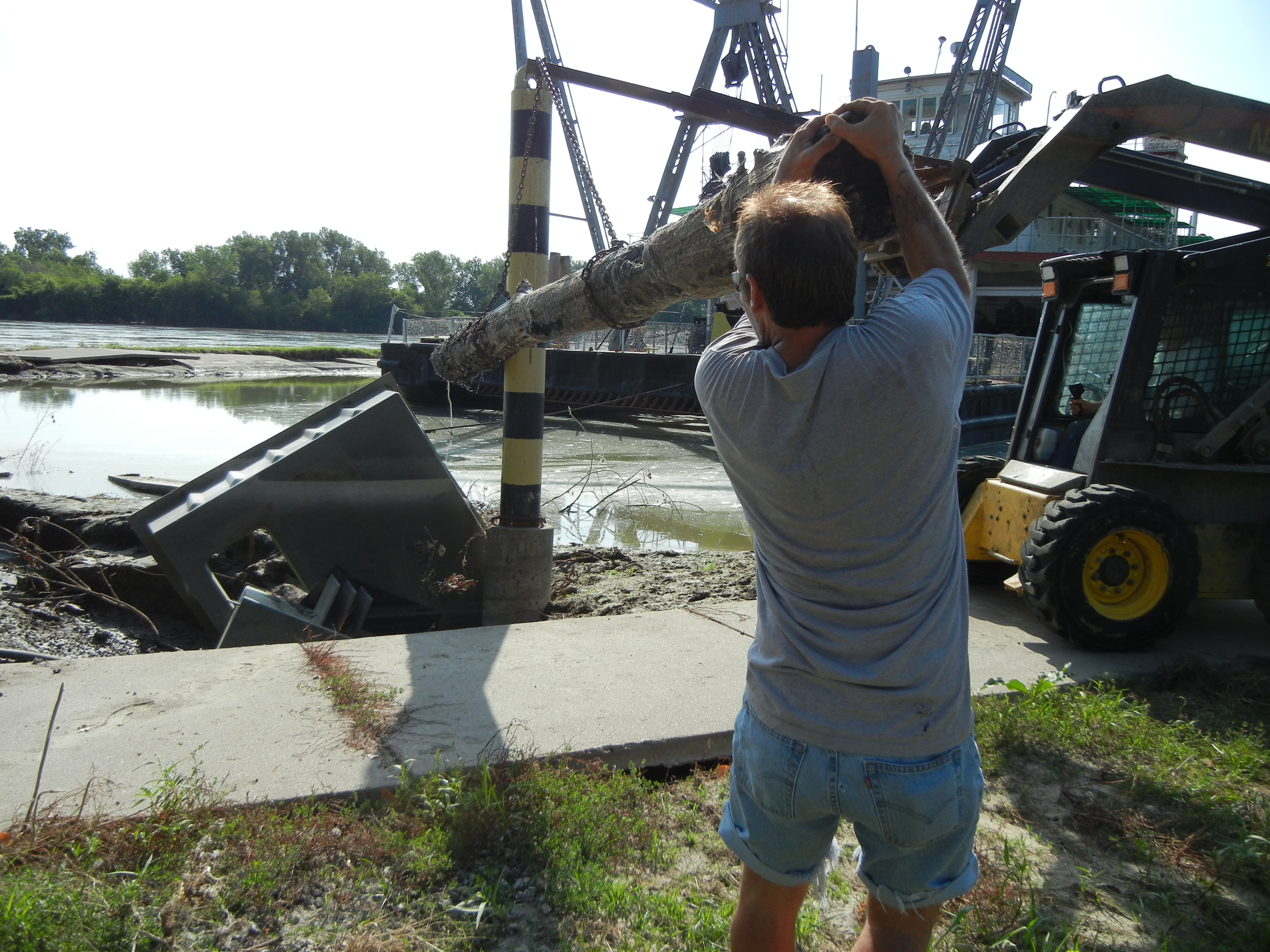 Man holding onto a log connected to machinery.