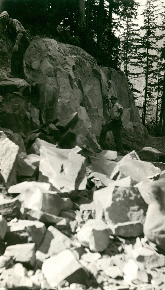 A man working at road construction along the Carbon River. A man working at road construction along the Carbon River with rocks in the foreground.