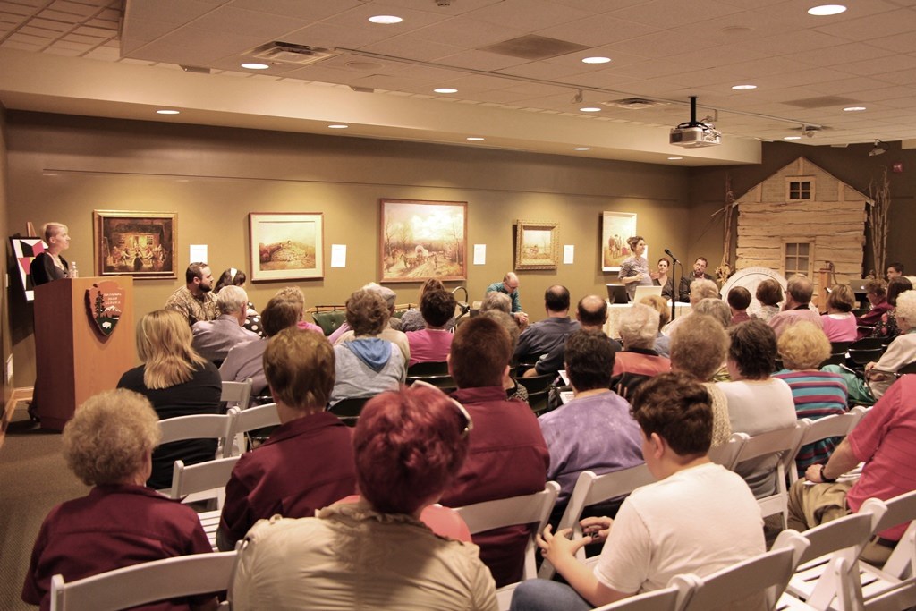 Velma Armstrong Paintings Audience watching a performance. Velma Armstrong paintings on the wall.