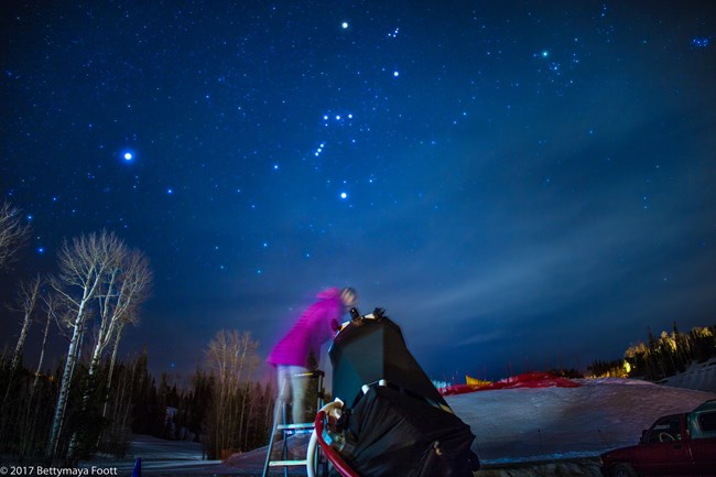 A park visitor looks through a telescope to the starry night sky at Cedar Breaks National Park, Utah.