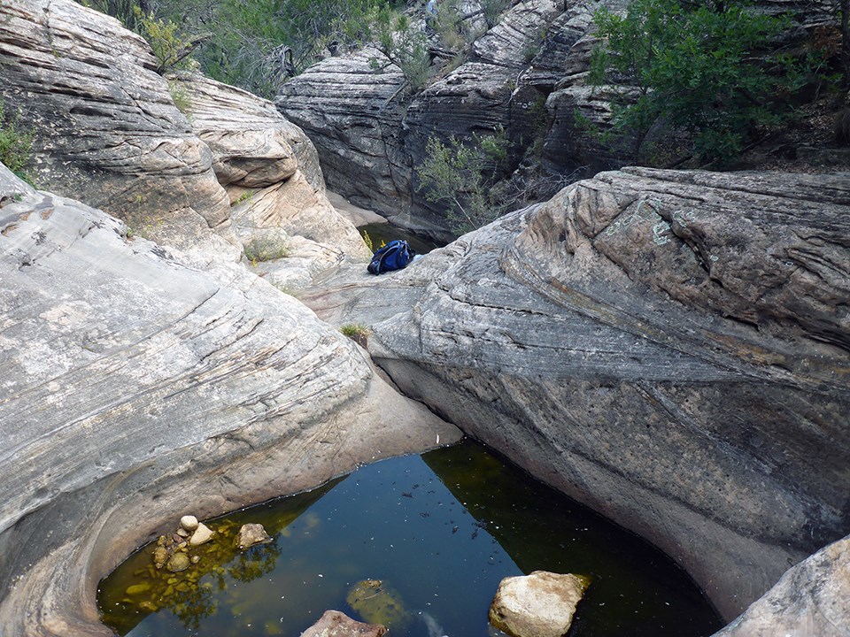 Pools nestled among boulders, with shrubs.