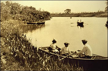 B&W photo of people rowing in boats on a lake.