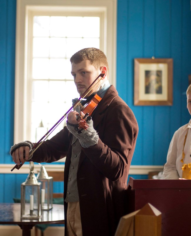 Man in 1840s suit playing the violin