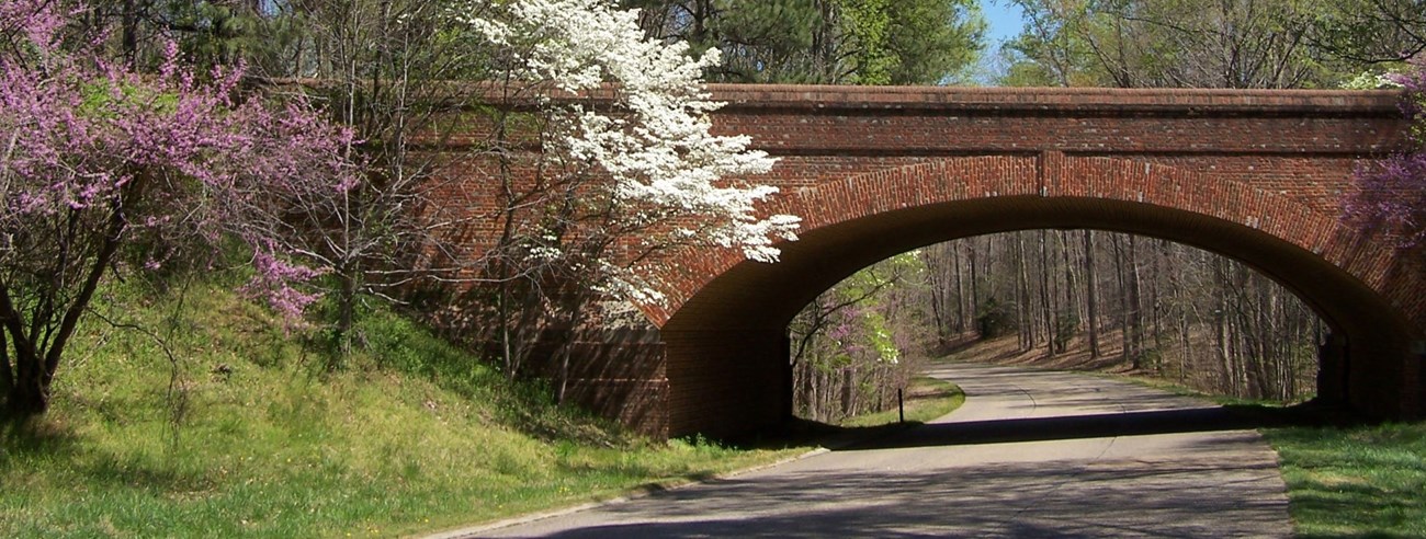 Colonial-Parkway_Reconstruct The colonial Parkway in spring time winding under an arched brick bridge