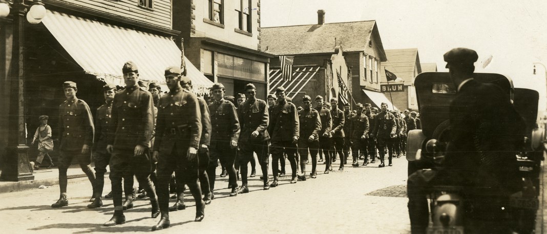 Uniformed soldiers march down a street.