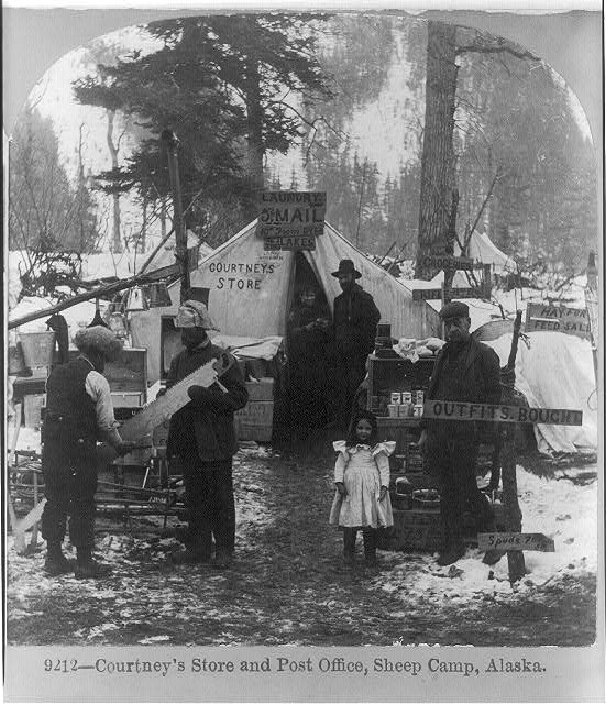 A group of people outside of a tent in the woods