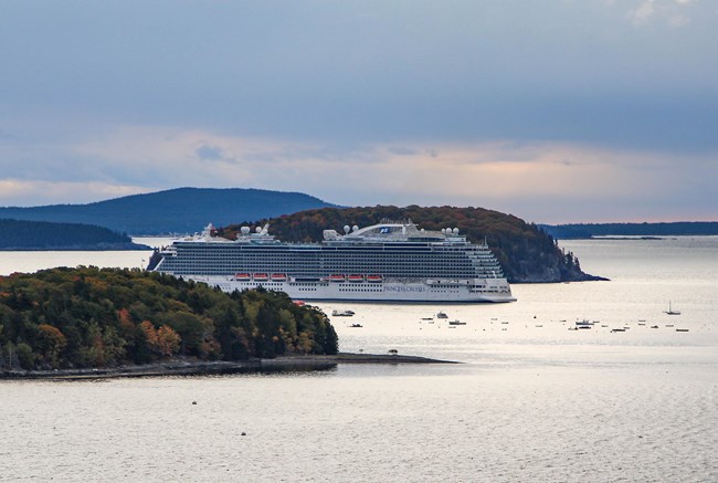 A full-sized cruise ship sails among small islands in Autumn