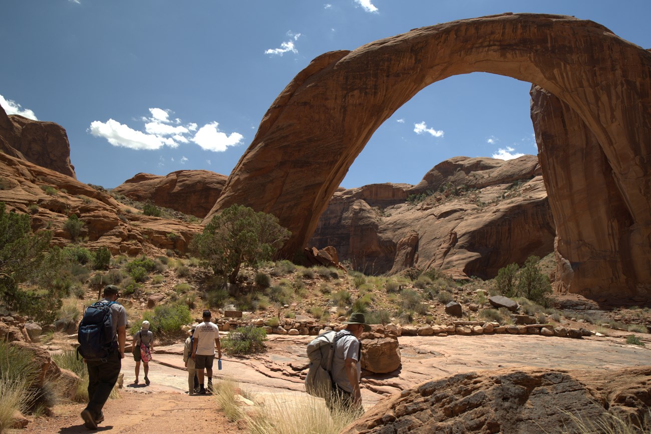 Rainbow Bridge A group of people hiking to a large rock arch.