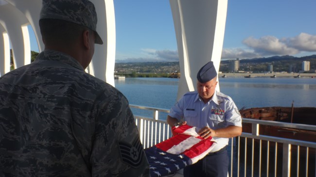 Two men in uniform fold an American flag.