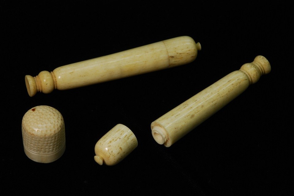 Photo of carved ivory thimble with two long, narrow ivory containers.