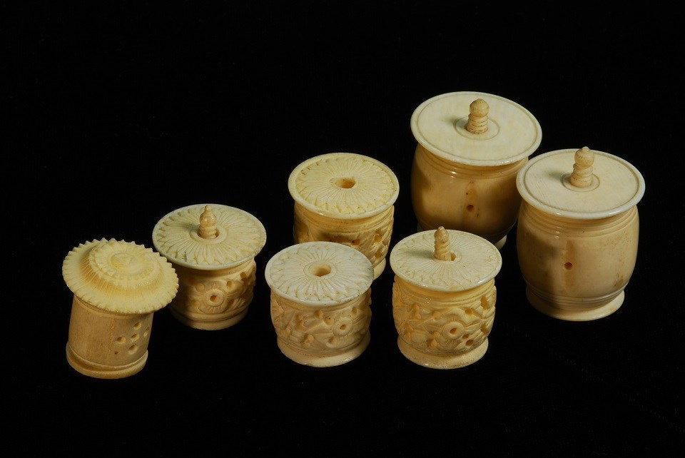 Photo of 7 round barrel-shaped thread barrels carved out of bone.