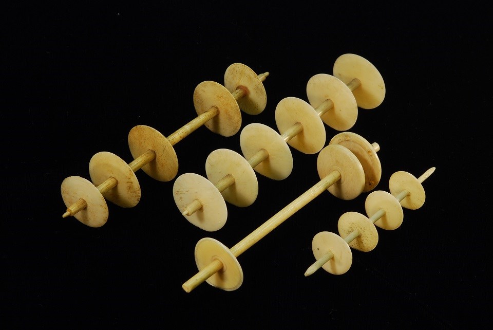 Four bone rods holding circular bone discs with holes in their center.