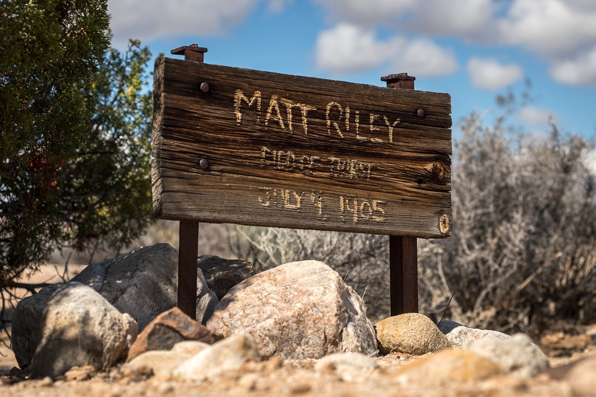 Color photo of the wooden sign marking Matt Riley's gravesite. It reads "Matt Riley died of thirst July 4, 1905."