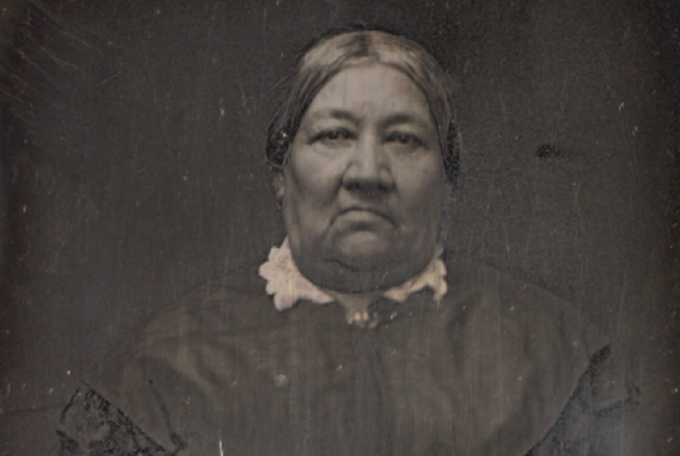 Black and white photo of woman in a dark dress with a white collar.