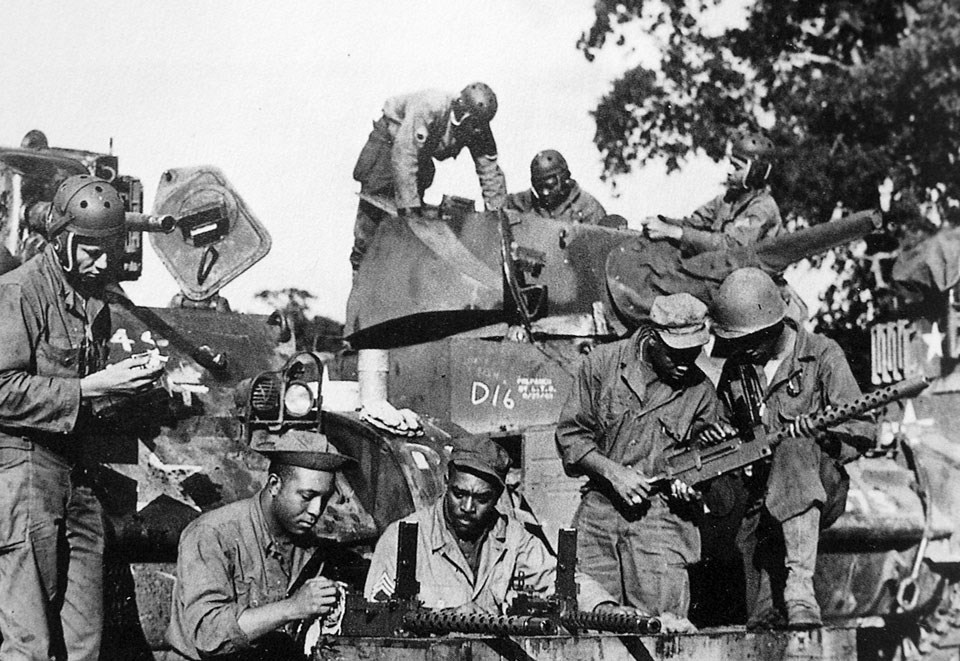 Several men around a tank cleaning weapons