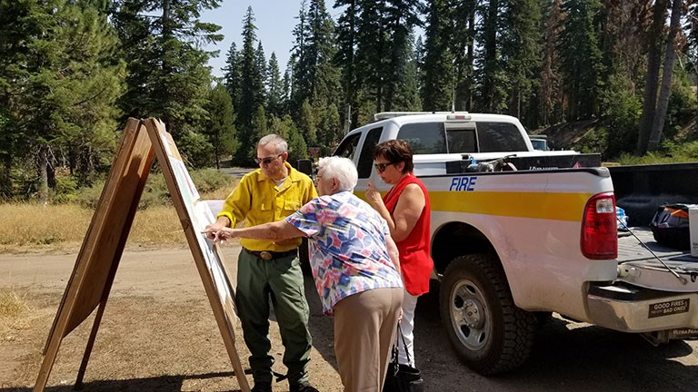 Donnell Fire Trapline A fire public information officer points to a recent fire map while explaining fire behavior to members of the public.
