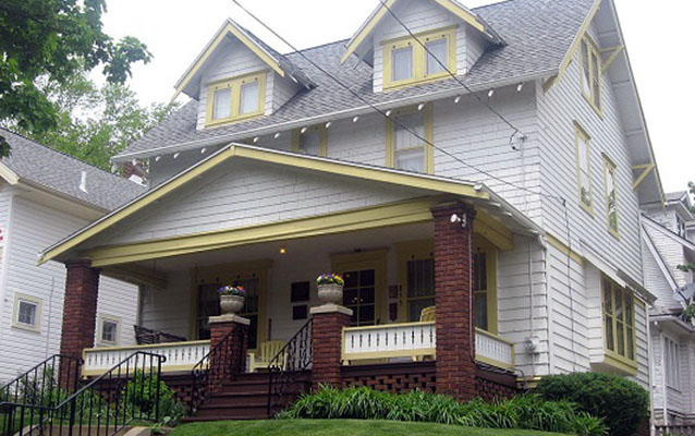 White house with yellow trim and a large front porch.